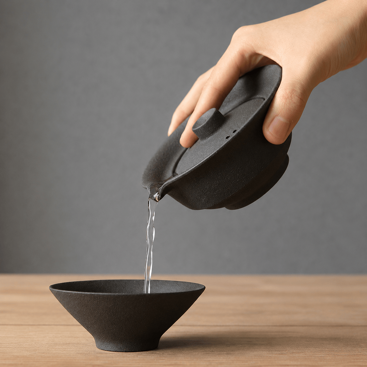 Gaiwan noir en gres qui verse du thé
